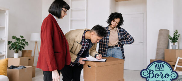Three young adults reviewing their own insurance policy paperwork beside moving boxes in a new home, with Boro Insurance Shoppe branding